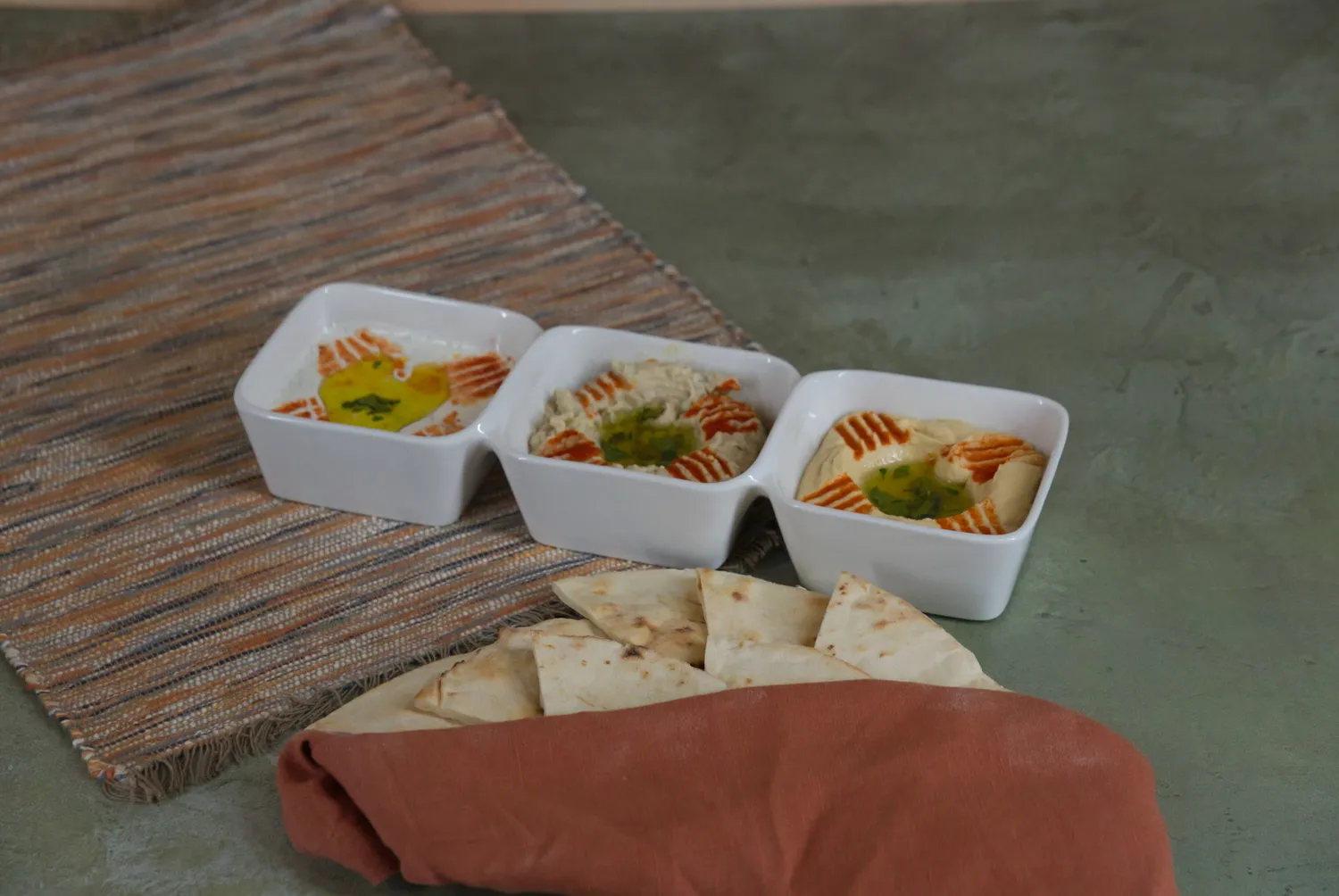 Flight of Dips, a trio of house-made hummus, baba ghannouj, and labneh with pita bread at Phoenician Garden in Fresno