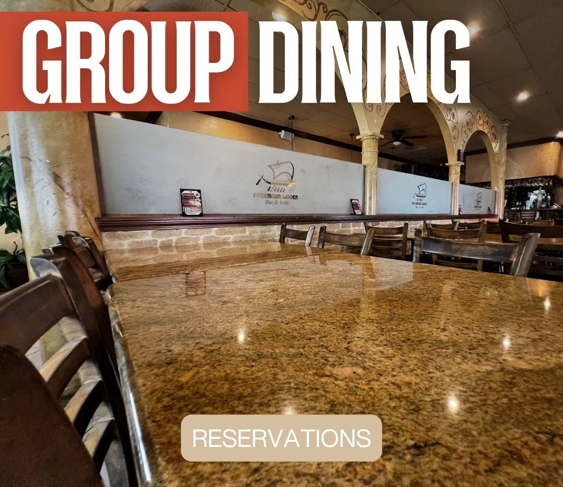 Large group enjoying Mediterranean dinner together at Phoenician Garden with shared platters and laughter