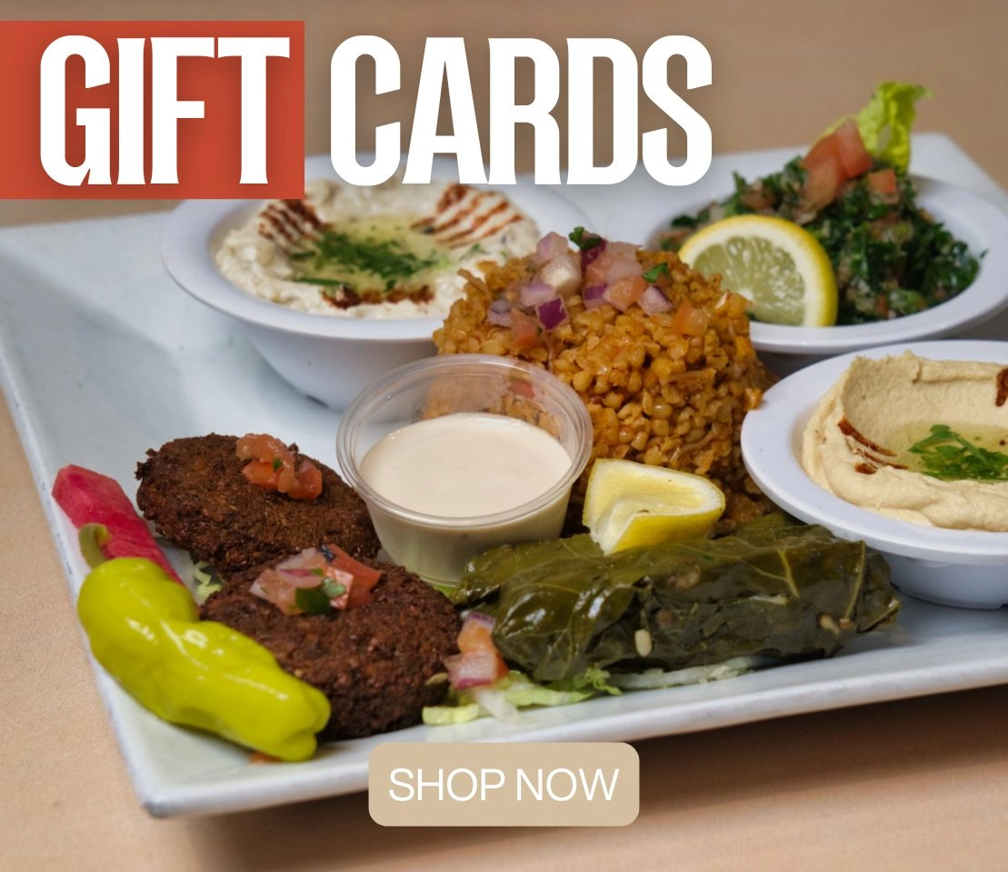 Phoenician Garden gift card surrounded by Mediterranean dishes and warm lighting